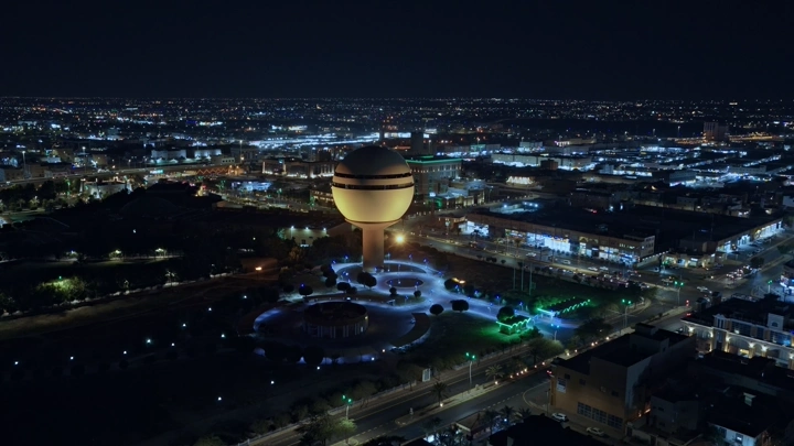 برج مياه بريدة مضاء ليلاً في القصيم، لقطة جوية.