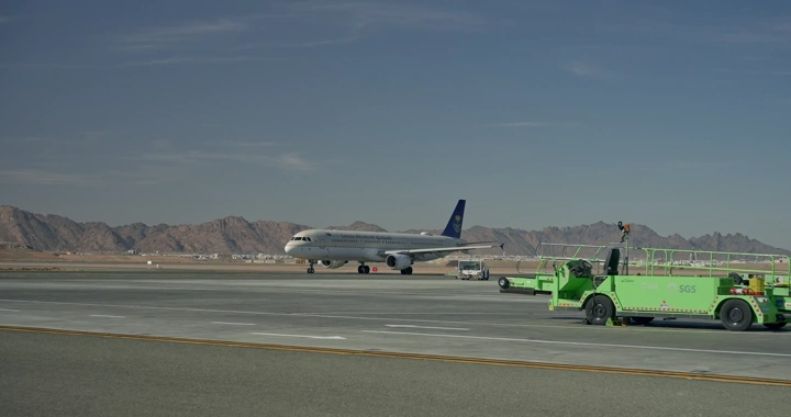 طائرة على مدرج المطار بجانب مركبة خضراء، تصوير نهاري.