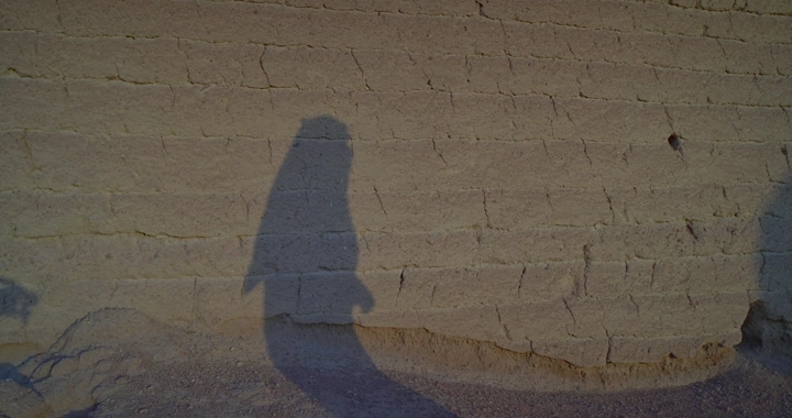 ظل رجل على جدار طيني في المساء، لقطة جانبية.