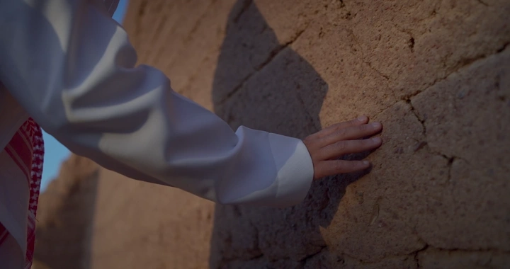 يد رجل تلمس جدار طيني في المساء، لقطة مقربة.