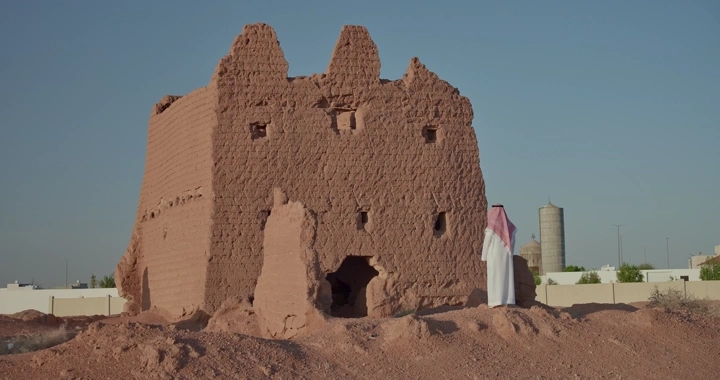 رجل يقف أمام بيت طيني قديم في النهار، لقطة أرضية.