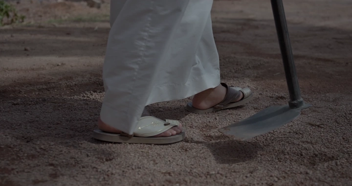 مزارع يرتدي ثوب يستخدم مجرفة في الحقل، لقطة مقربة.