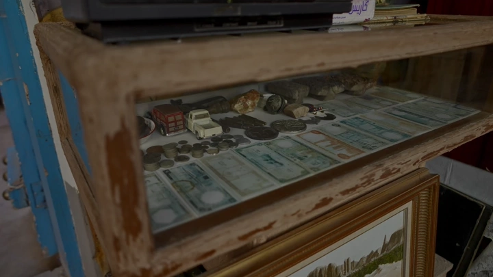 مجموعة من العملات القديمة في صندوق عرض خشبي، لقطة داخلية.