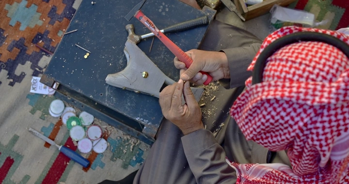 حرفي يصنع مبخرة يدوية على سجادة ملونة، لقطة علوية.