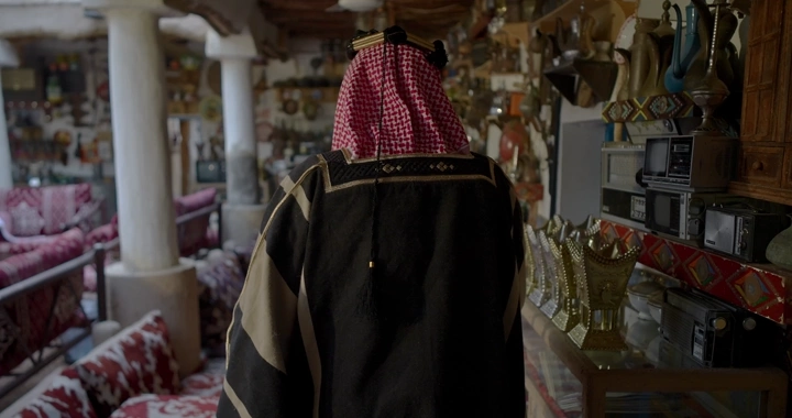 رجل يرتدي بشت سعودي في متحف تقليدي، لقطة داخلية.