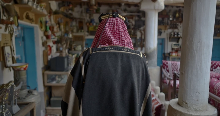 رجل يرتدي بشت سعودي في متحف تقليدي، لقطة من الخلف.