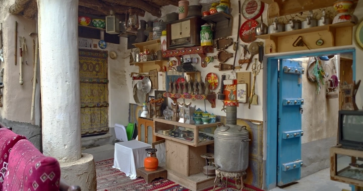 رجل يمشي بين مجموعة من الأدوات التقليدية في متحف تراثي، لقطة داخلية.