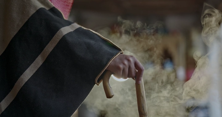 رجل يرتدي بشت ويمسك عصا في مكان قديم، لقطة مقربة.