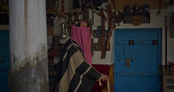 رجل يرتدي بشت سعودي في متحف تقليدي، لقطة داخلية.