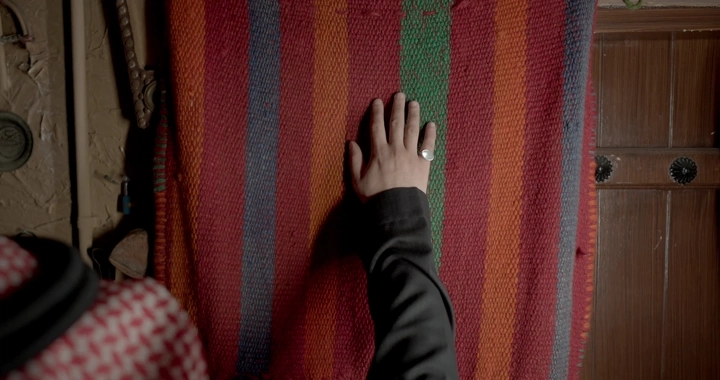 يد تلمس نسيج سدو ملون في غرفة تقليدية، لقطة قريبة.