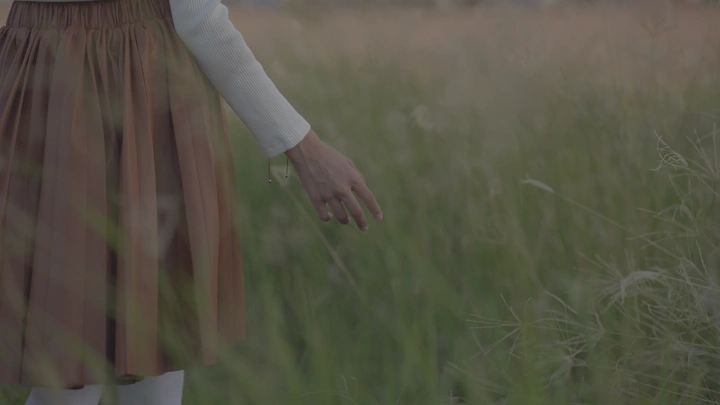 يد تمتد في حقل عشبي، لقطة جانبية.