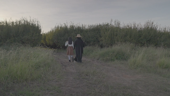 شخصان يسيران في مزرعة رمان، لقطة من الخلف.