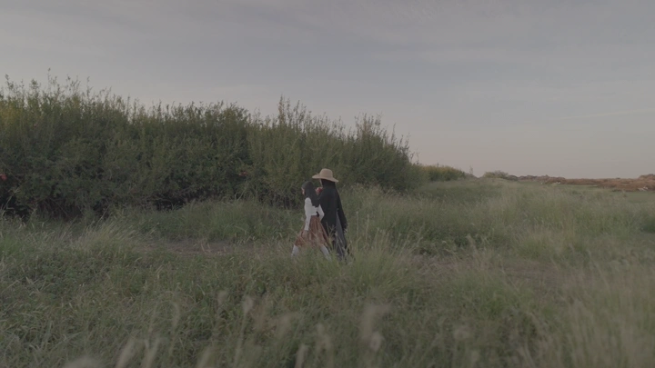 شخصان يسيران في مزرعة رمان عند الغروب، لقطة واسعة.