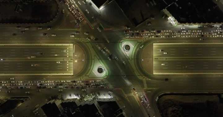 تقاطع شوارع مضاء في حائل ليلاً، لقطة جوية.