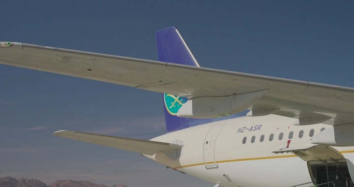 طائرة السعودية في مطار تحت سماء زرقاء، لقطة جانبية.