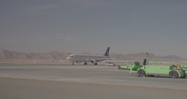 طائرة على مدرج مطار في منطقة جبلية، لقطة نهارية.