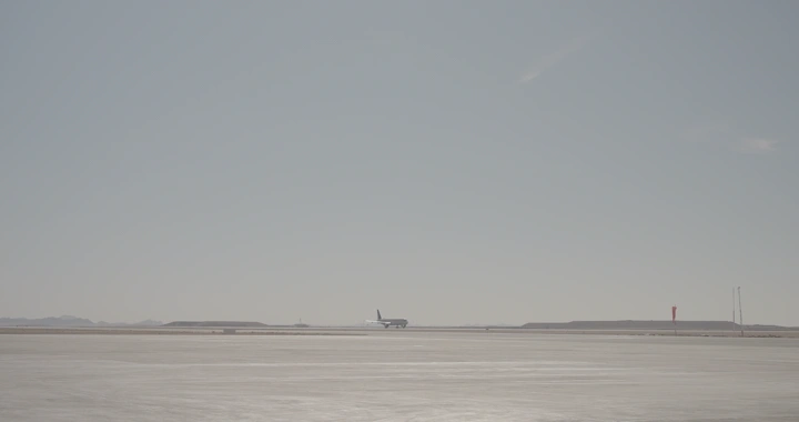 طائرة تقلع من مدرج في يوم مشمس، لقطة بعيدة.