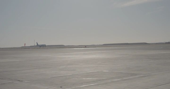 طائرة تقلع من مدرج مطار في وضح النهار، لقطة بعيدة.