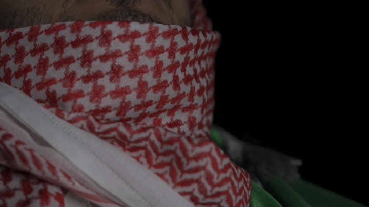 رجل بالثوب والشماغ السعودية ويحيط نفسه بعلم السعودية، لقطة مقربة.