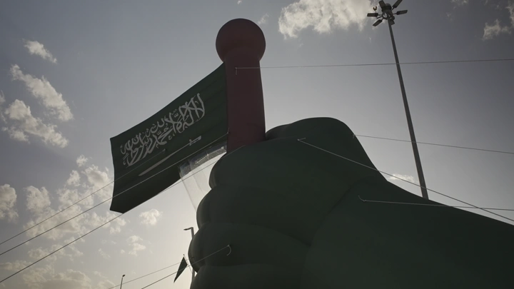 علم سعودي مرفوع في حائل خلال اليوم الوطني، لقطة من الأسفل.