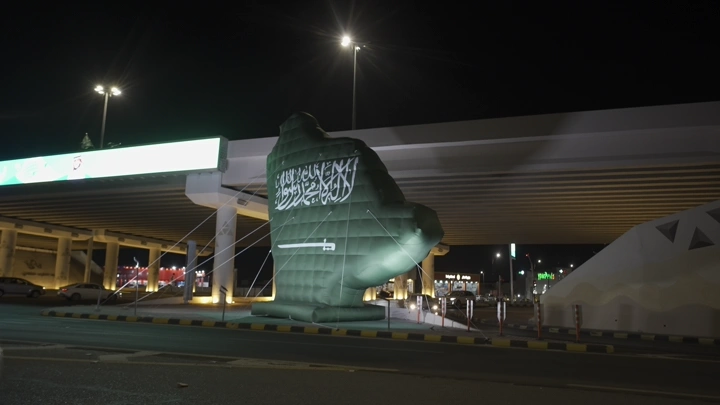 تمثال أخضر على شكل خريطة السعودية مضاء في حائل ليلاً، لقطة ليلية.