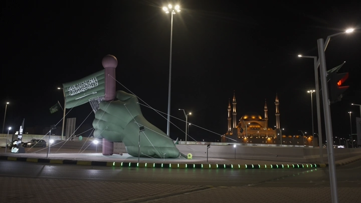 مجسم يد يحمل علم السعودية في حائل ليلاً، تصوير ليلي.
