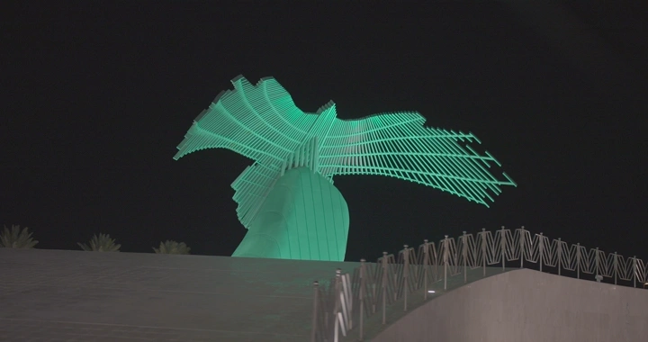 دوار الصقر مضاء باللون الأخضر في حائل، لقطة ليلية.