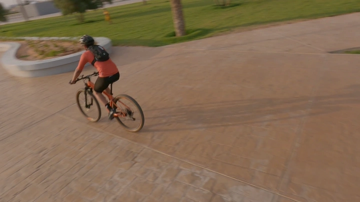 شخص يركب دراجة في حديقة، لقطة درون من الأعلى.