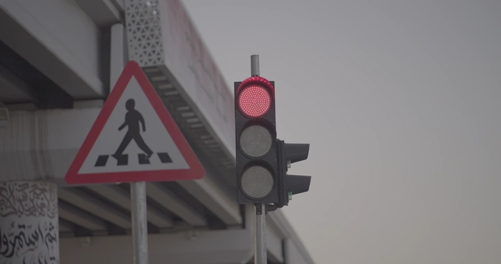 إشارة مرور حمراء بجانب لافتة مشاة، تصوير نهاري.