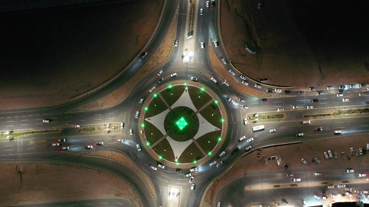 دوار مضاء ليلاً مع عدد كبير من السيارات، لقطة جوية.