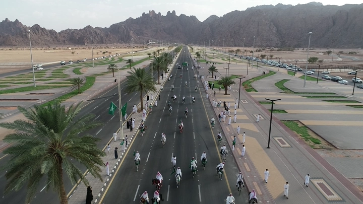 مسيرة خيول في طريق واسع خلال اليوم الوطني في حائل، لقطة جوية.