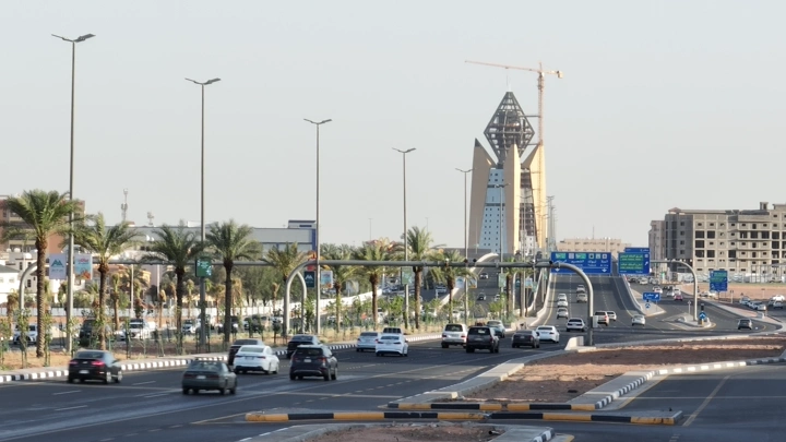 طريق دائري في حائل مع حركة مرور نهارية، منظر من مستوى الشارع.