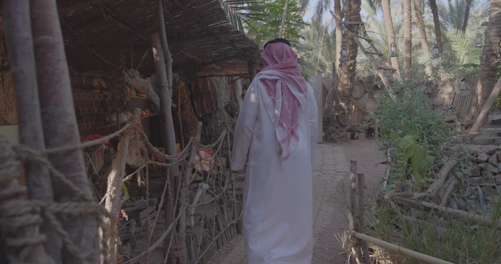 رجل يرتدي الزي السعودي في سوق شعبي، لقطة نهارية.