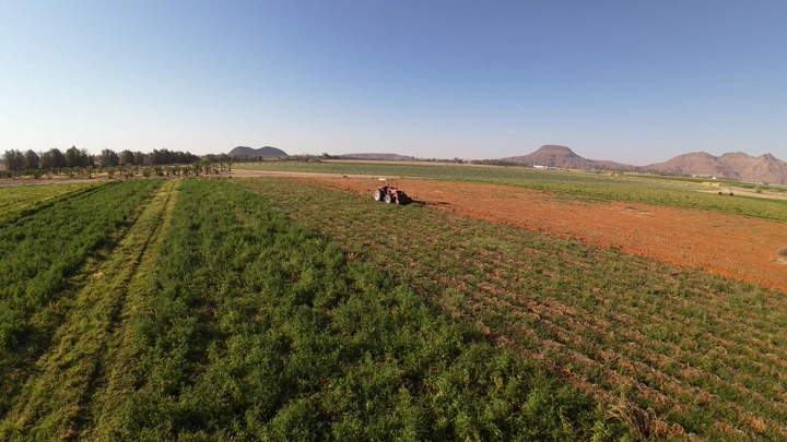 مزرعة واسعة مع جرار يحرث الأرض، لقطة جوية.