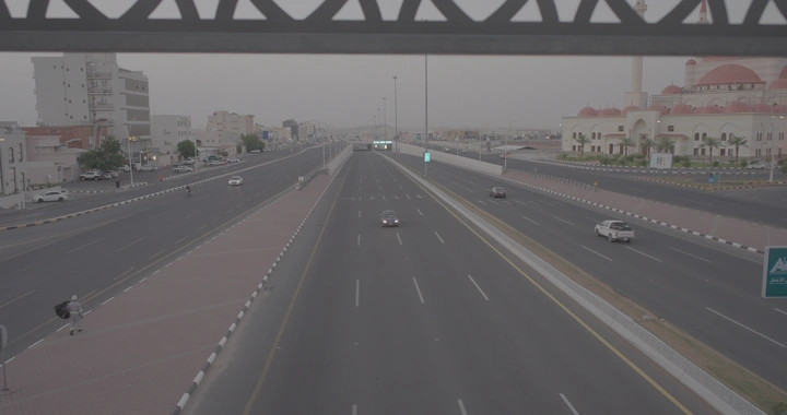 طريق سريع تحت جسر مشاة في حائل مع ظهور رجل، لقطة من الأعلى.