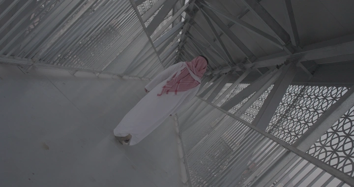 رجل يمشي على جسر مشاة حديث في يوم غائم، زاوية مائلة.