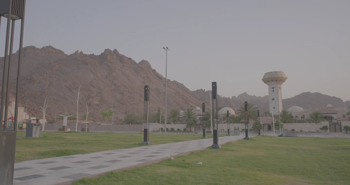 رجل يمشي في حديقة في حائل مع جبال في الخلفية، لقطة نهارية.