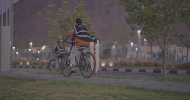 شخص يركب دراجة في ممشى الفجر بحائل، لقطة من الخلف.