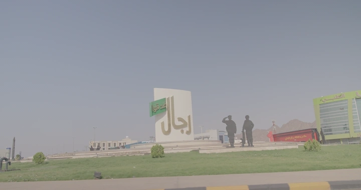 دوار الأسمنت في حائل مع لافتة كبيرة وعلم، لقطة نهارية.