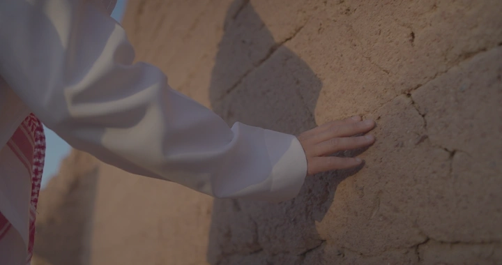 يد تلمس جدار طيني في ضوء النهار، لقطة قريبة.