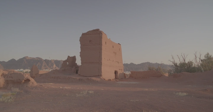 بيت طيني في الصحراء عند الغروب مع مرور رجل، لقطة واسعة.