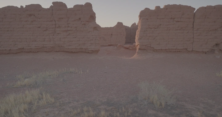 رجل يمشي داخل بيت طيني قديم في الصحراء عند الغروب، لقطة أرضية.