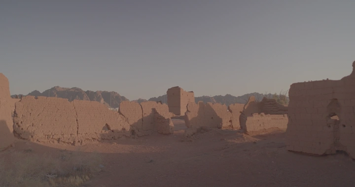 أطلال بيت طيني في الصحراء عند الغروب، لقطة واسعة.