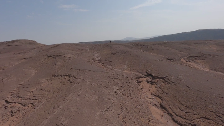 شخص يقف على حافة فوهة بركان الهتيمه في حائل، لقطة جوية.