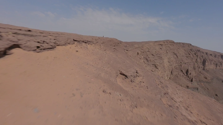 شخص يقف على حافة فوهة بركان الهتيمه في حائل، لقطة جوية.