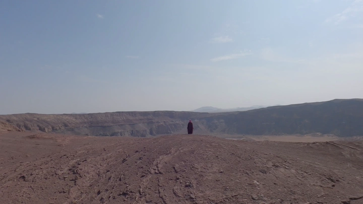 شخص يقف على حافة فوهة بركان الهتيمه في حائل، لقطة جوية.