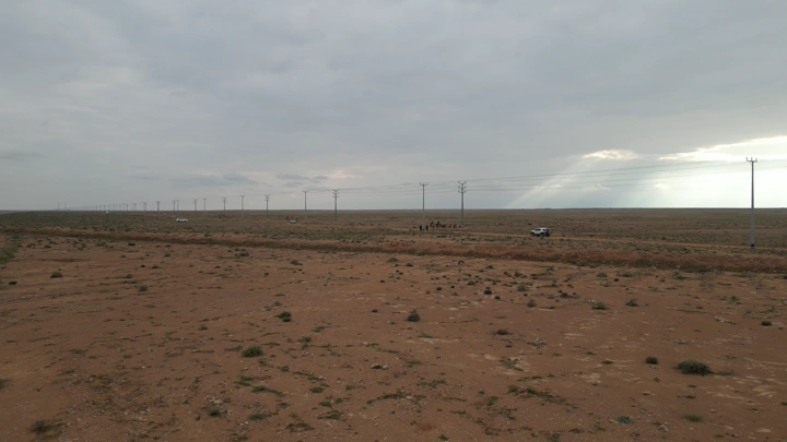 صحراء واسعة مع سيارات وابل تحت السماء الغائمة، لقطة جوية.