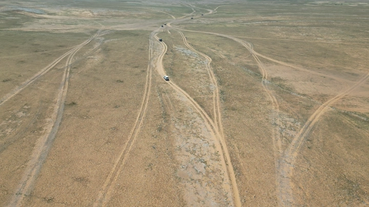 سيارات تسير على طرق ترابية في صحراء واسعة، لقطة جوية.