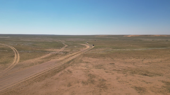 طريق صحراوي في الربيع تحت سماء زرقاء، لقطة جوية.