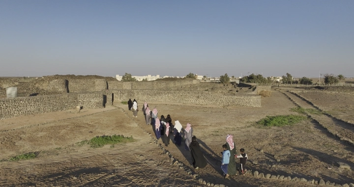 مجموعة أشخاص يسيرون بجانب قصر خراش الأثري في قرية فيد، لقطة جوية.
